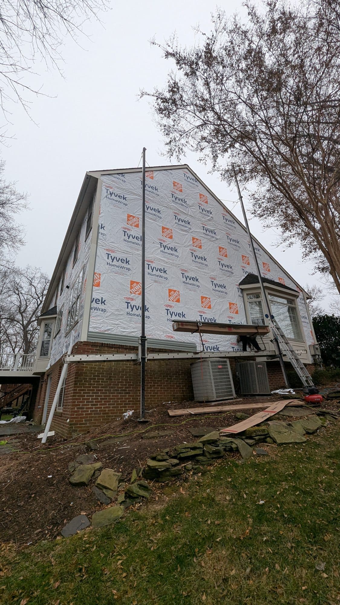Home wrapped in house wrap with staging set up along the base for siding installation